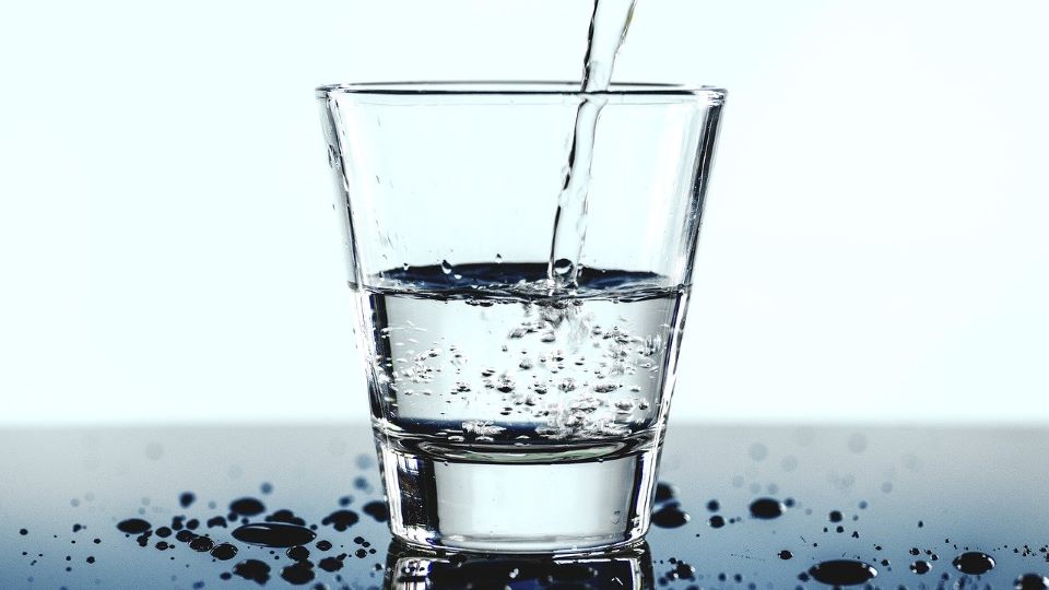 Fyller upp dricksvatten från kran i glas