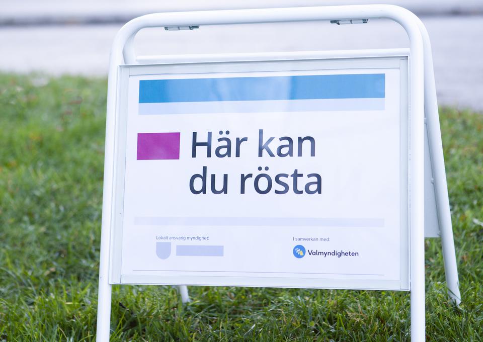 En skylt som står i gräset. På skylten står det Här kan du rösta.