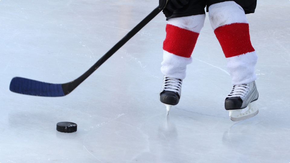 Ishockeyspelare med klubba och puck på isen.